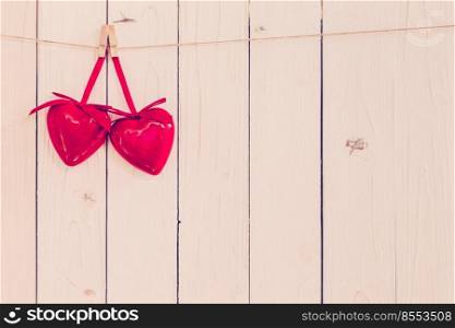 Two red heart hanging on white wood background with space.