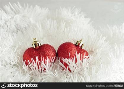 Two red heart shape baubles with white tinsel