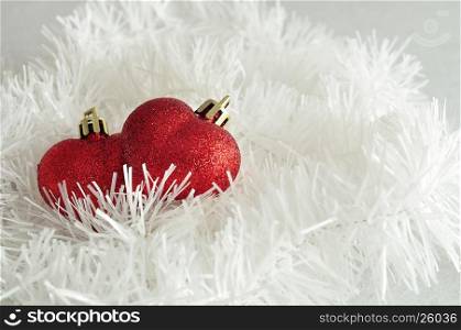 Two red heart shape baubles with white tinsel