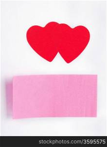 Two red hearts and a sticky-note stuck on paper sheet