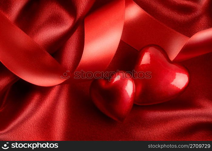 Two red hearts with ribbon on satin