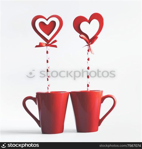 Two red mugs with hearts lollipop standing on white background. Declaration of love and Valentines day concept