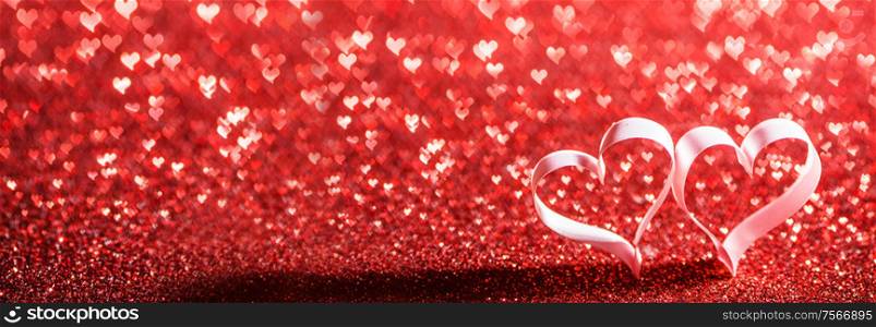 Two red ribbon hearts on glitter background with copy space for text, Valentines day concept. Red ribbon hearts on glitters