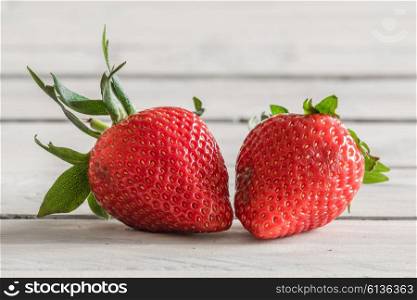 Two red strawberries on a wooden table