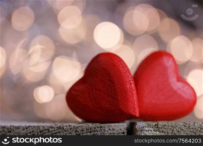 Two red wooden hearts symbol of love on background with beautiful bokeh party lights, Saint Valentine Day celebration. Red hearts symbol of love