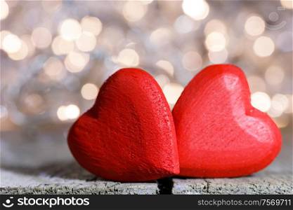 Two red wooden hearts symbol of love on background with beautiful bokeh party lights, Saint Valentine Day celebration. Red hearts symbol of love