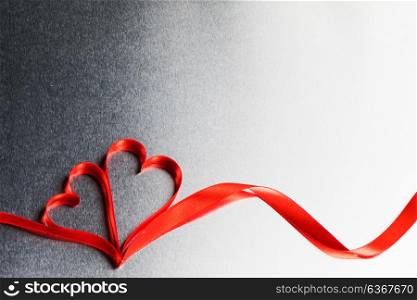 Two ribbon hearts. Two red ribbon hearts on metal background with copy space