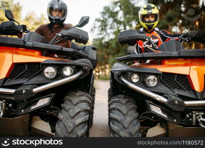 Two riders in helmets and equipment on quad bikes, front view, closeup. Male quadbike drivers, atv riding, extreme sport