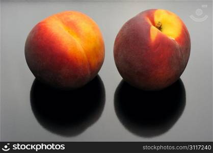 Two ripe peach on a black background.