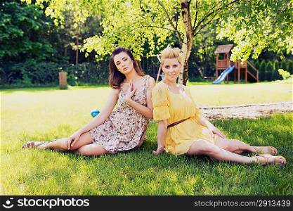Two romantic girls sitting on flower meadow