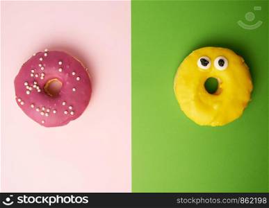 two round donuts with sprinkles on a pink-green background, top view