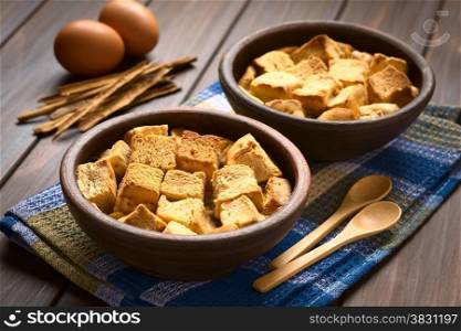 Two rustic bowls of bread pudding made of diced stale bread, milk, egg, cinnamon, sugar and butter, photographed with natural light (Selective Focus, Focus one third into the first bread pudding)