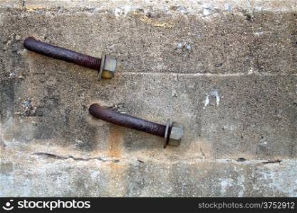 Two Rusty Bent Lag Bolt in Concrete.
