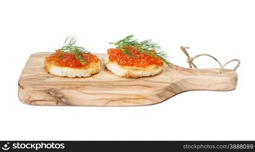Two sandwiches with red caviar on the olive cutting board