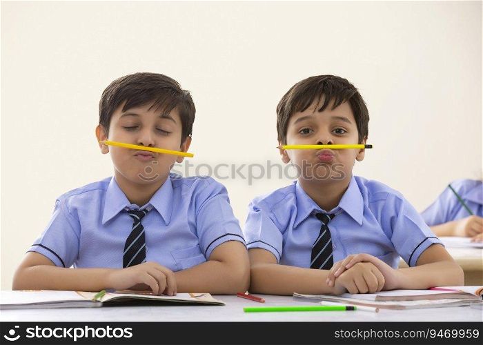 two school boys playing with pencils in class