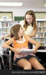 Two school girls in the library - one is in a wheelchair.