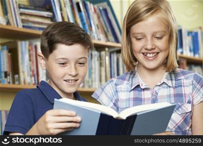 Two School Pupils Reading Book In Library