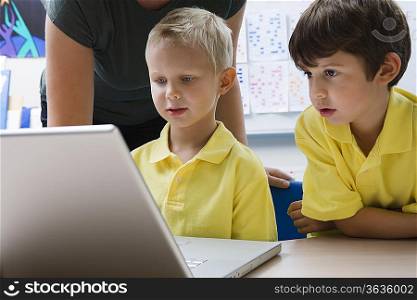 Two schoolboys sit learning computer technology