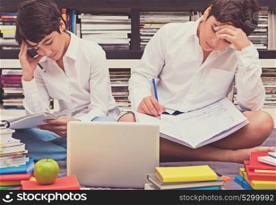 Two schoolboys sitting in the library and thinking about a difficult task, doing home work, education in the high school, back to school