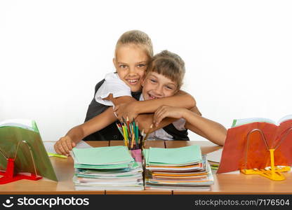 Two schoolgirls are sitting at a desk looking at textbooks