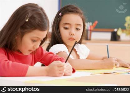 Two schoolgirls painting in an art class