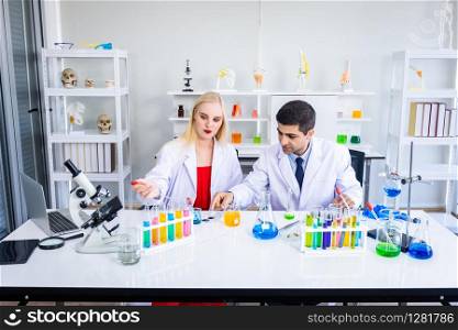 Two scientists are working holding looking at test tube with sample in a chemistry lab scientist or young female and male researcher are doing investigations in Laboratory analysis background