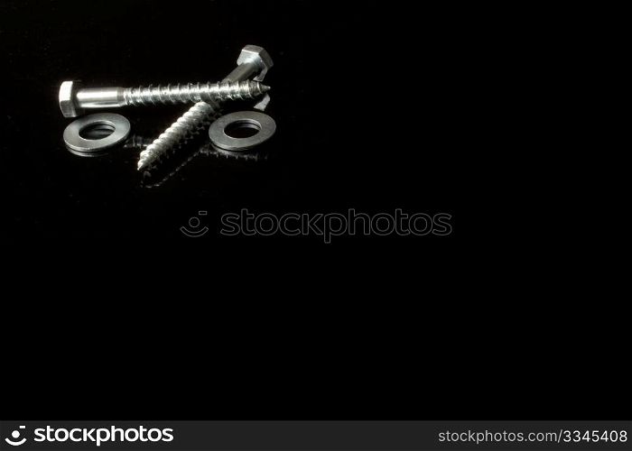 two screws and crossed over a black background and its reflection