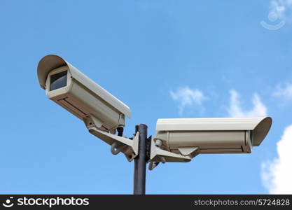 Two security cameras against blue sky