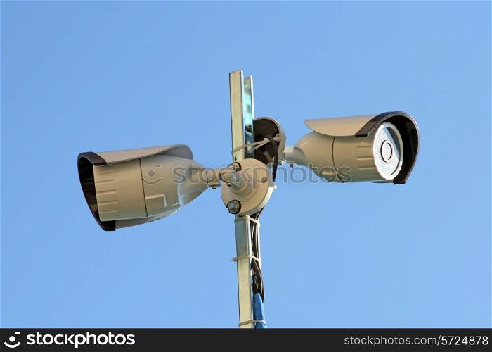 Two security cameras against blue sky