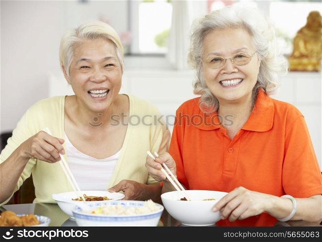 Two Senior Chinese Women Sitting At Home Eating Meal
