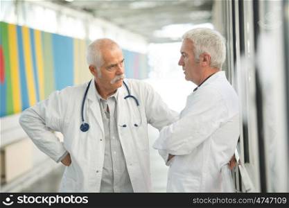 two senior doctors talking in hospital corridor