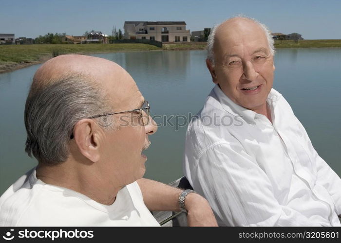 Two senior men sitting on a bench at the lakeside