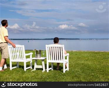 Two senior people in patio chairs drinking champagne by Chesapeake bay