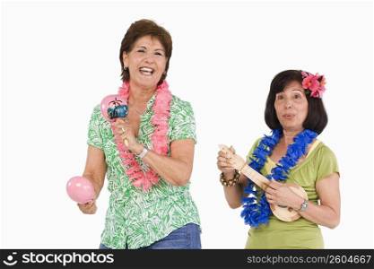 Two senior women playing ukulele and maracas