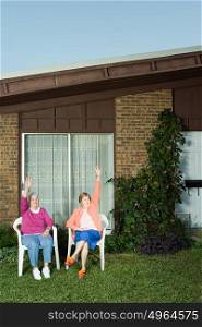 Two senior women sat in garden waving