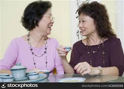 Two senior women sitting at a table and looking at each other