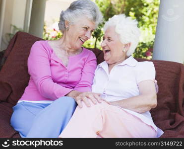 Two senior women sitting outdoors on a chair