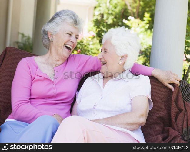Two senior women sitting outdoors on a chair