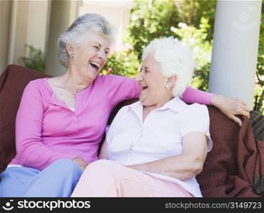 Two senior women sitting outdoors on a chair
