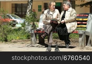 Two senior women talking on a park bench