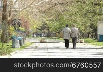 Two senior women walking along the alley, rear view