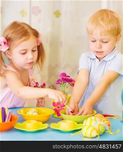 Two serious children paint Easter eggs at home, using colorful decoration, Christian holiday concept