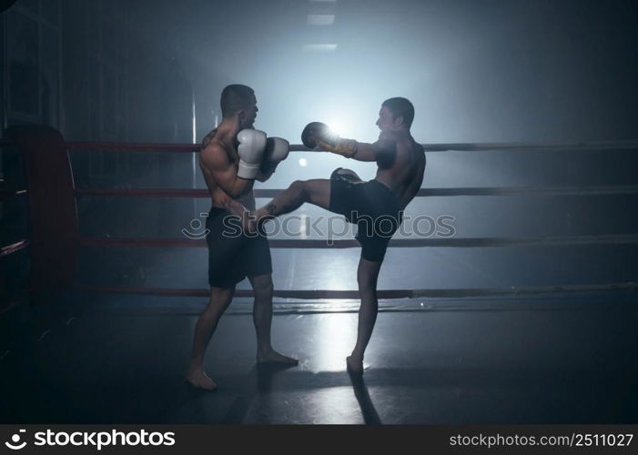 Two shirtless muscular man fighting Kick boxing combat in boxing ring. High quality photo. Two shirtless muscular man fighting Kick boxing combat in boxing ring.