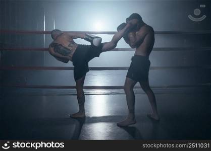 Two shirtless muscular man fighting Kick boxing combat in boxing ring. High quality photo. Two shirtless muscular man fighting Kick boxing combat in boxing ring.