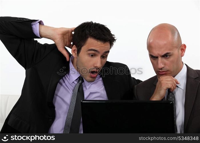 Two shocked office workers holding laptop