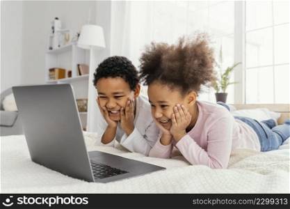 two siblings home together playing laptop