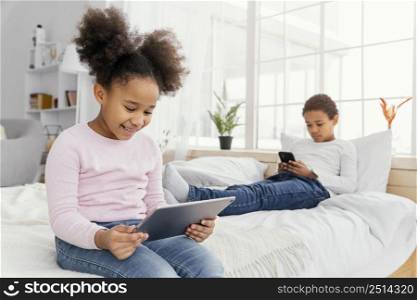 two siblings home together playing tablet smartphone