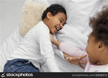 two siblings playing bed home