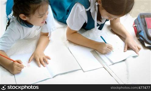 two sister girl writes a book. The decision of lessons. girl lay down drawing the picture