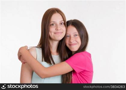Two sisters and a teenager girl hugging look in frame